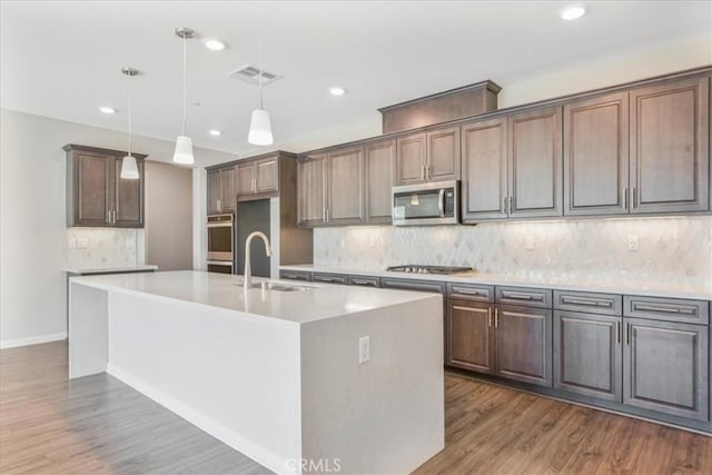 34428 Burnt Pine Rd, Murrieta, CA 92563 - kitchen with stainless steel appliances, a sink, an island with sink, wood finished floors, and recessed lighting