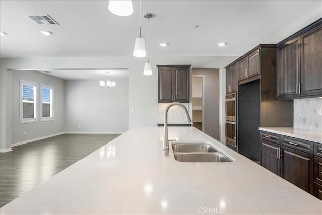 34428 Burnt Pine Rd, Murrieta, CA 92563 - kitchen with a sink, dark brown cabinetry, backsplash, open floor plan, and wood finished floors