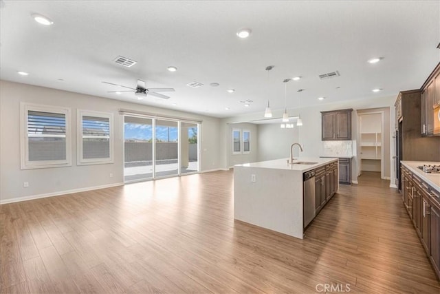 34428 Burnt Pine Rd, Murrieta, CA 92563 - kitchen with open floor plan, a center island with sink, light wood-style flooring, light countertops, and recessed lighting