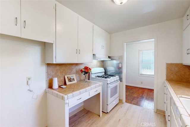 2234 Perkins Ave, Oroville, CA 95966 - kitchen featuring gas range gas stove, ventilation hood, light wood-type flooring, white cabinets, and tile countertops