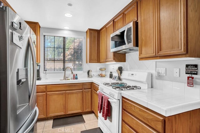 1440 Patricia Ave Unit 102, Simi Valley, CA 93065 - kitchen featuring stainless steel appliances, a sink, brown cabinetry, backsplash, and light tile patterned floors