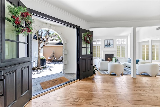 19365 Woodlands Dr, Huntington Beach, CA 92648 - entryway featuring a lit fireplace, healthy amount of natural light, crown molding, and light wood-type flooring