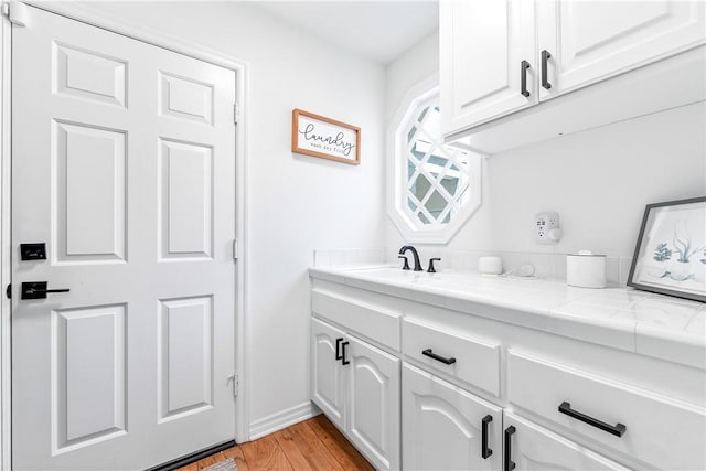 19365 Woodlands Dr, Huntington Beach, CA 92648 - laundry area with light wood-style flooring, a sink, and baseboards