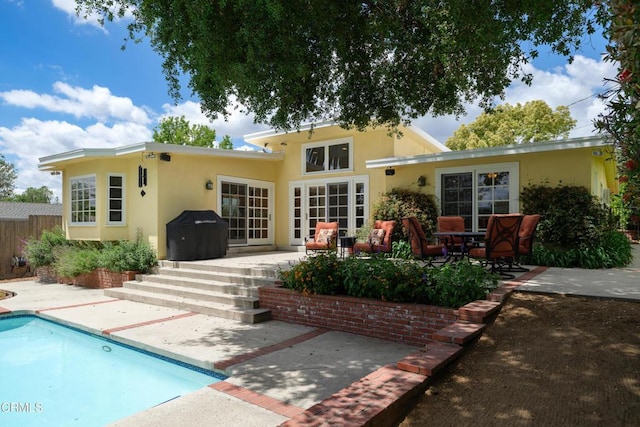 rear view of house featuring a patio area, stucco siding, and an outdoor pool