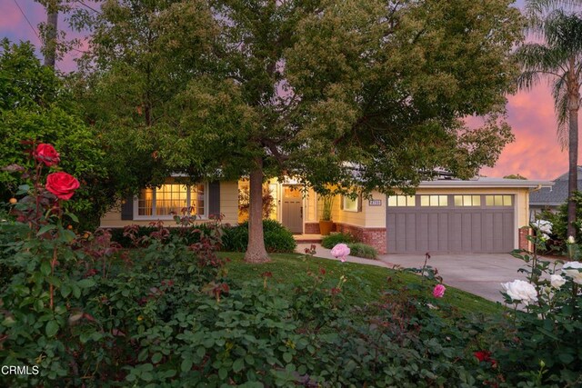 view of front of home with brick siding, an attached garage, and concrete driveway