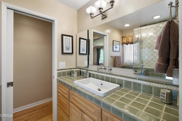 full bath featuring baseboards, wood finished floors, vanity, and a shower