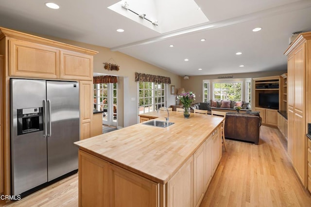 kitchen featuring stainless steel refrigerator with ice dispenser, a sink, wooden counters, light wood finished floors, and light brown cabinetry