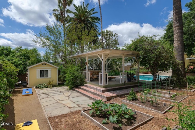 view of yard featuring a patio, a vegetable garden, an outbuilding, and fence
