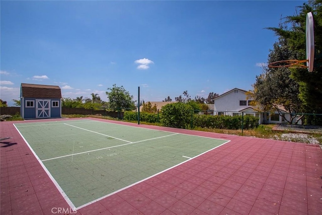 view of tennis court featuring a storage unit, fence, an outbuilding, and community basketball court