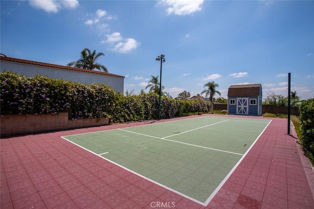 view of tennis court featuring community basketball court, a shed, fence, and an outbuilding