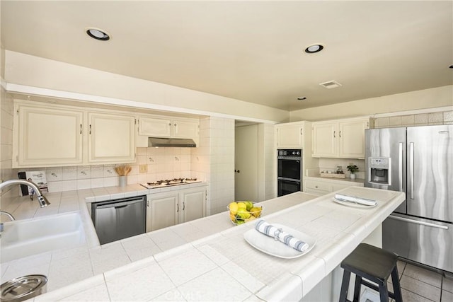 5642 Burlingame Ave, Buena Park, CA 90621 - kitchen with appliances with stainless steel finishes, tile countertops, a sink, under cabinet range hood, and tasteful backsplash