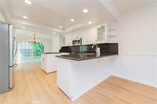 29355 Shell Cv, Laguna Niguel, CA 92677 - kitchen with stainless steel appliances, a peninsula, light wood-style floors, white cabinets, and crown molding