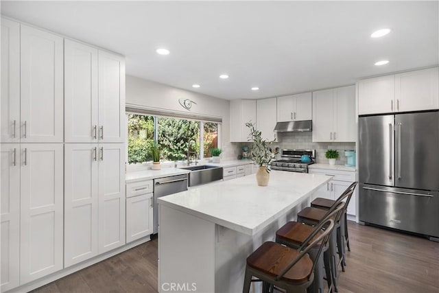 33028 Christina Dr, Dana Point, CA 92629 - kitchen featuring stainless steel appliances, under cabinet range hood, a center island, a breakfast bar, and dark wood-style flooring