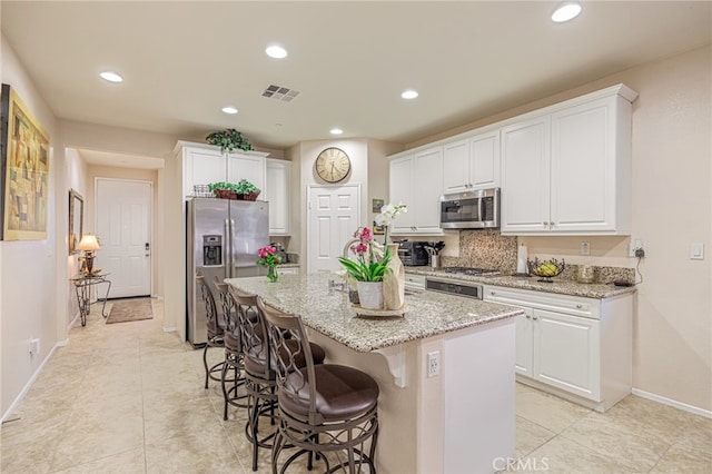 kitchen featuring stainless steel appliances, white cabinets, a kitchen island with sink, and recessed lighting