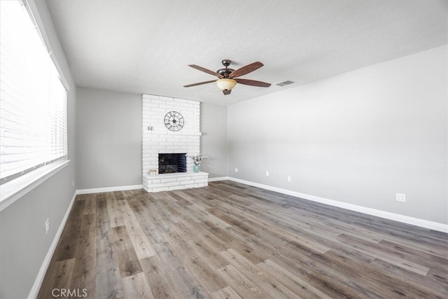 14351 Cronese Rd, Apple Valley, CA 92307 - unfurnished living room featuring a ceiling fan, a brick fireplace, wood finished floors, baseboards, and a textured ceiling