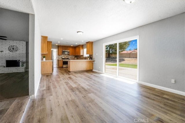14351 Cronese Rd, Apple Valley, CA 92307 - unfurnished living room with a fireplace, light wood-style flooring, baseboards, ceiling fan, and a textured ceiling