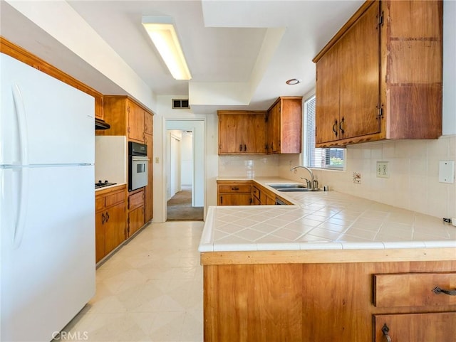 11674 Oak Ln, Yucaipa, CA 92399 - kitchen with freestanding refrigerator, stainless steel oven, brown cabinetry, and a peninsula