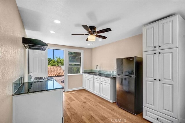 521 W Whiting Ave, Fullerton, CA 92832 - kitchen with freestanding refrigerator, exhaust hood, light wood finished floors, ceiling fan, and white cabinetry