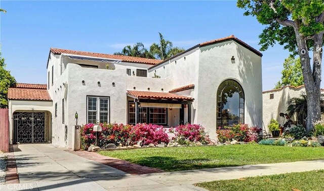 521 W Whiting Ave, Fullerton, CA 92832 - mediterranean / spanish-style home featuring stucco siding, a tiled roof, concrete driveway, and a front lawn