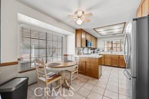 kitchen featuring appliances with stainless steel finishes, brown cabinetry, a peninsula, light countertops, and light tile patterned floors