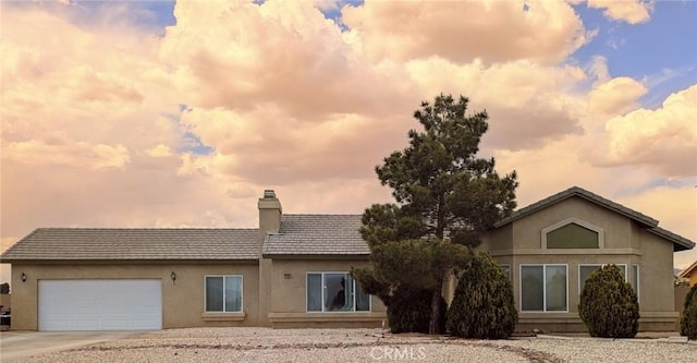 22132 Esaws Rd, Apple Valley, CA 92307 - back of property at dusk featuring a chimney, an attached garage, concrete driveway, and stucco siding