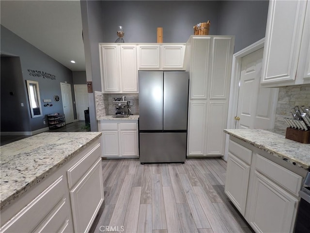 22132 Esaws Rd, Apple Valley, CA 92307 - kitchen with freestanding refrigerator, tasteful backsplash, vaulted ceiling, white cabinets, and light wood-style floors