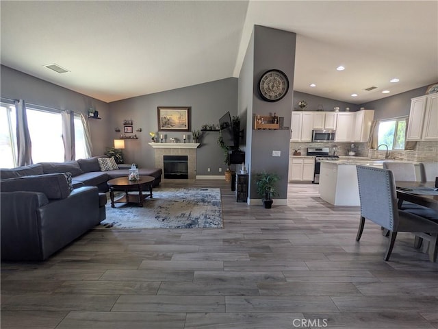 22132 Esaws Rd, Apple Valley, CA 92307 - living room with lofted ceiling, a tiled fireplace, wood finished floors, baseboards, and recessed lighting