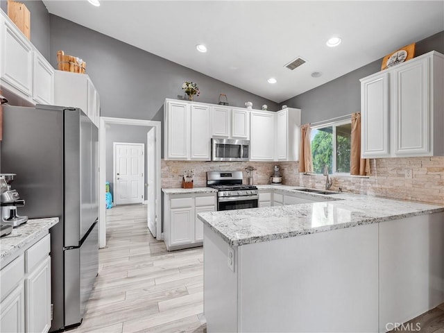22132 Esaws Rd, Apple Valley, CA 92307 - kitchen with stainless steel appliances, a sink, vaulted ceiling, a peninsula, and decorative backsplash