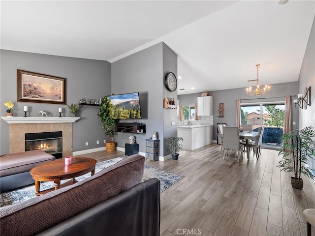 22132 Esaws Rd, Apple Valley, CA 92307 - living room with a chandelier, lofted ceiling, light wood-style floors, a tiled fireplace, and baseboards