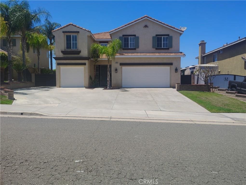 mediterranean / spanish-style house with an attached garage, stucco siding, driveway, and a tile roof