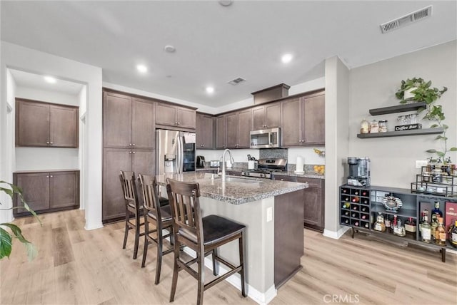 16548 Monteviejo St, Fontana, CA 92336 - kitchen featuring stainless steel appliances, a sink, light wood-type flooring, a breakfast bar, and light stone countertops
