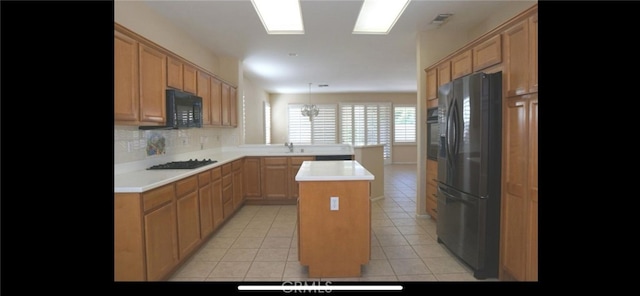 78379 Kistler Way, Palm Desert, CA 92211 - kitchen with black appliances, light tile patterned flooring, a peninsula, light countertops, and a center island