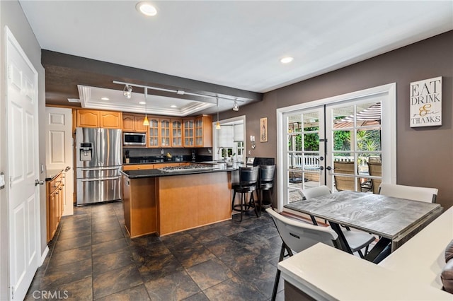 kitchen with stainless steel appliances, recessed lighting, glass insert cabinets, a raised ceiling, and a peninsula