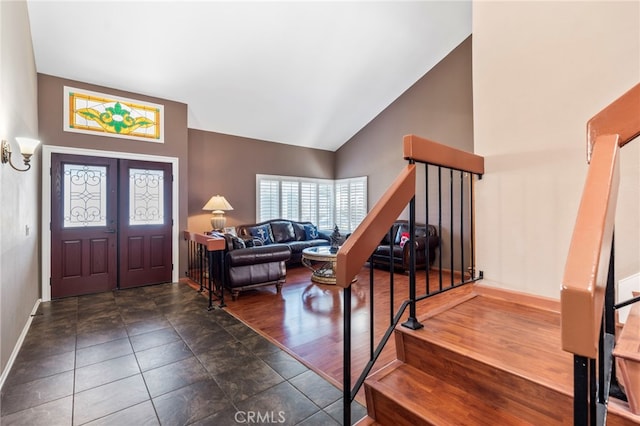 entryway with baseboards, vaulted ceiling, and stairway