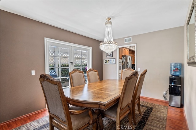 dining room featuring a chandelier, wood finished floors, and baseboards