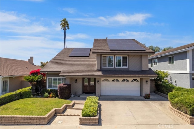 traditional-style home featuring driveway, a front yard, an attached garage, solar panels, and stucco siding