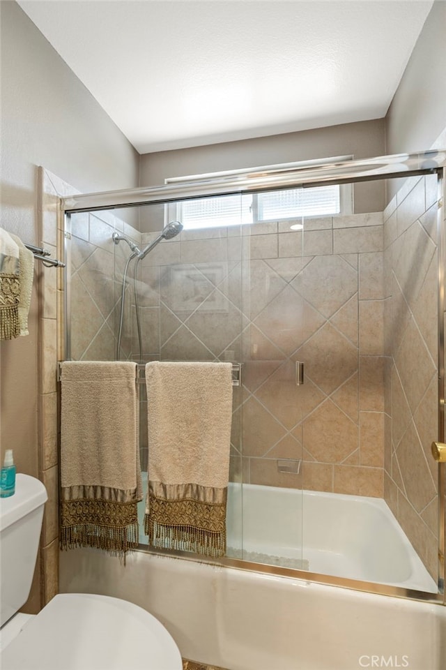 bathroom with toilet, shower / bath combination with glass door, and healthy amount of natural light