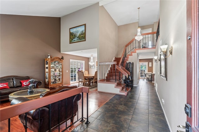 foyer entrance with high vaulted ceiling, healthy amount of natural light, stairs, and baseboards