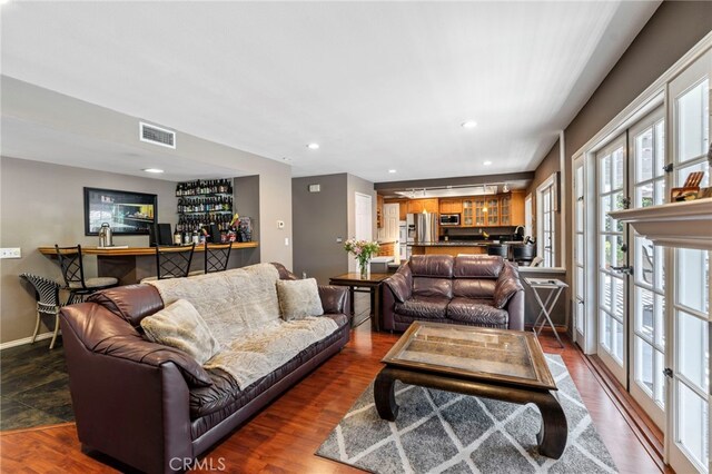 living area with a bar, recessed lighting, dark wood-type flooring, and baseboards