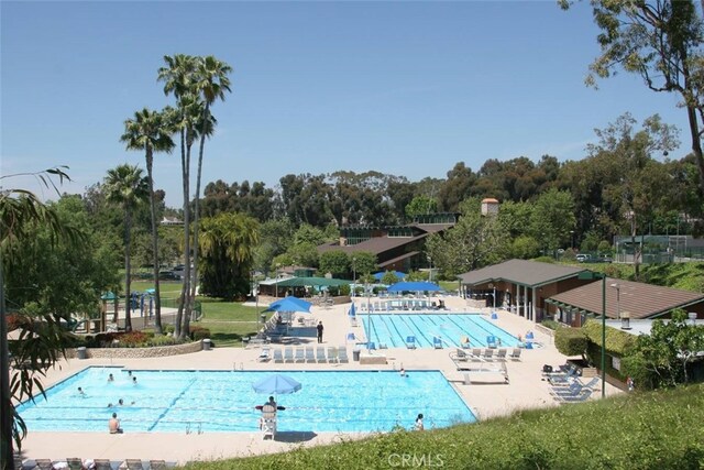 community pool featuring a patio and view of wooded area