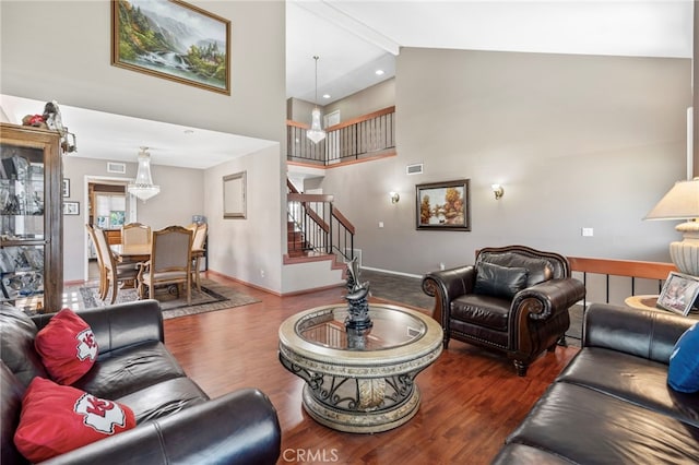 living area with wood finished floors, stairs, high vaulted ceiling, and baseboards