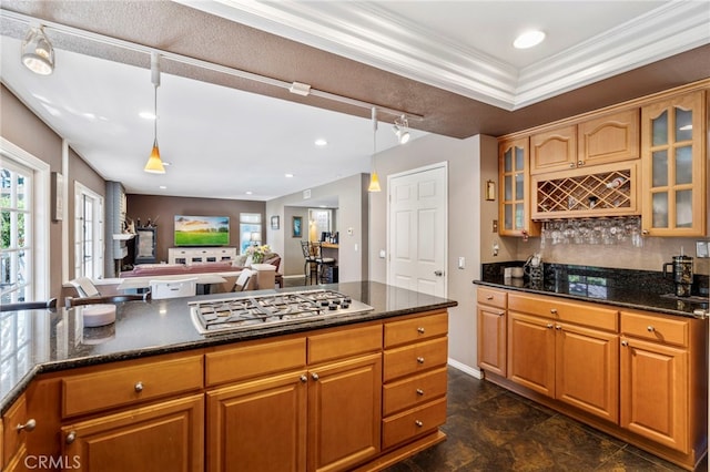 kitchen featuring stainless steel gas stovetop, dark stone counters, decorative backsplash, glass insert cabinets, and ornamental molding