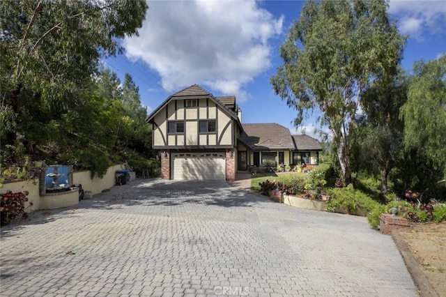 24300 Sylvan Glen Rd, Calabasas, CA 91302 - tudor-style house with a garage, decorative driveway, and brick siding
