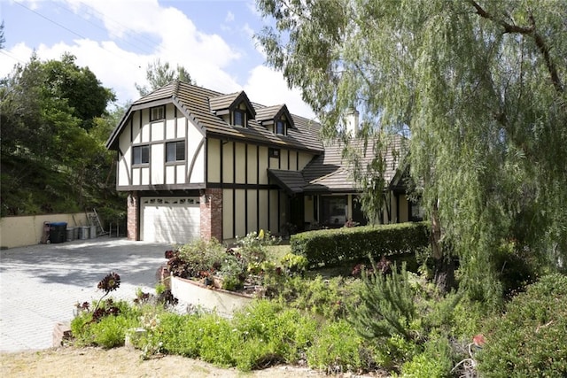 24300 Sylvan Glen Rd, Calabasas, CA 91302 - view of front facade with decorative driveway, an attached garage, brick siding, and board and batten siding