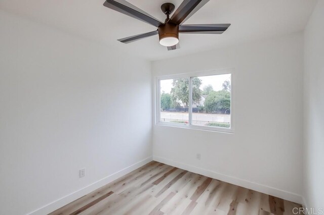 spare room featuring baseboards, light wood-type flooring, and a ceiling fan
