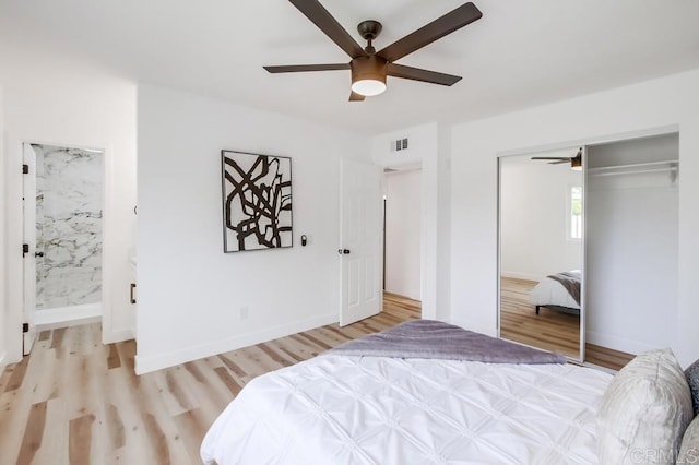 bedroom with light wood-type flooring, a closet, ceiling fan, ensuite bath, and baseboards