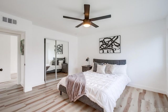 bedroom with light wood-type flooring, a closet, ceiling fan, and baseboards