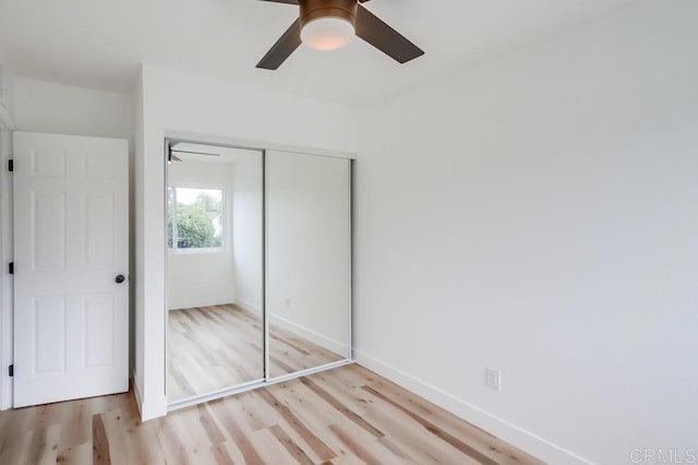 unfurnished bedroom featuring light wood-type flooring, a closet, baseboards, and a ceiling fan