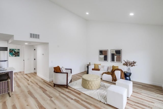 living area with high vaulted ceiling, light wood-style floors, recessed lighting, and baseboards