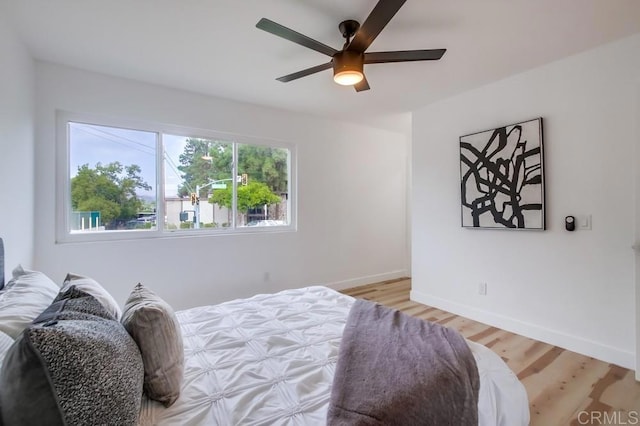 bedroom featuring light wood finished floors, baseboards, and ceiling fan
